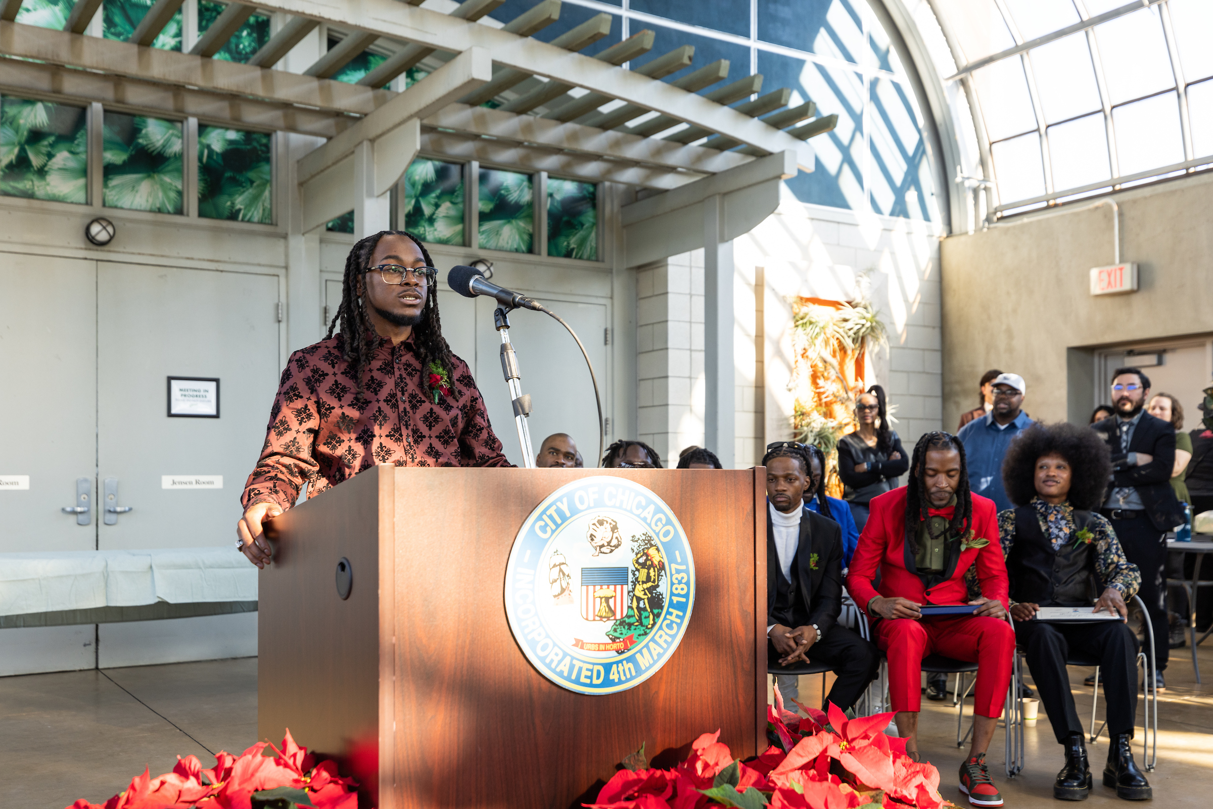 A Greencorps Chicago graduates speaks at a podium in front on his fellow graduates